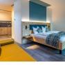Modern apartment with wooden bed, yellow sofa and kitchenette.