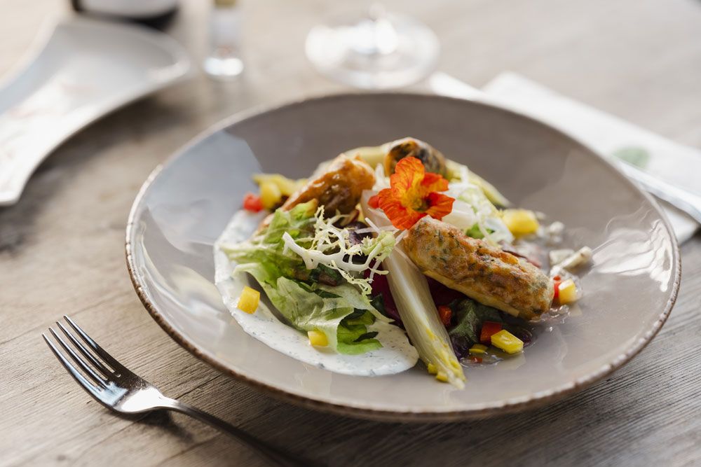 A plate with spring rolls, salad and edible flowers.