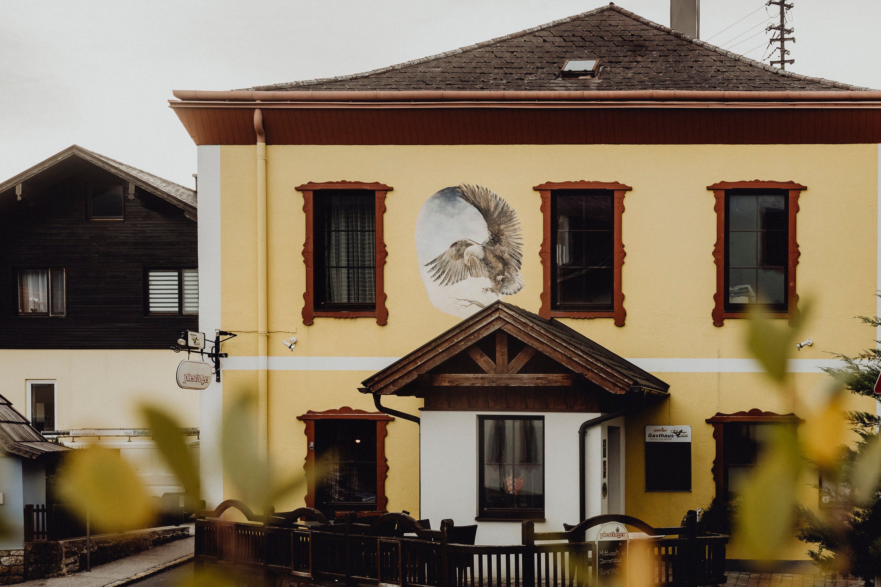 Yellow building with a mural of an eagle and red window frames.