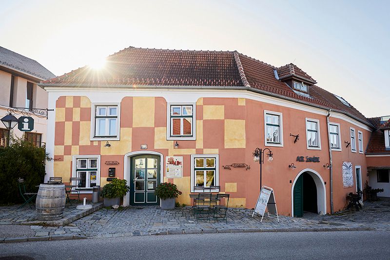 Historic building with yellow and red façade, sunshine in the background.