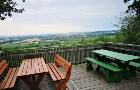 Viewing platform with wooden benches and tables, view of the wide landscape and fields.