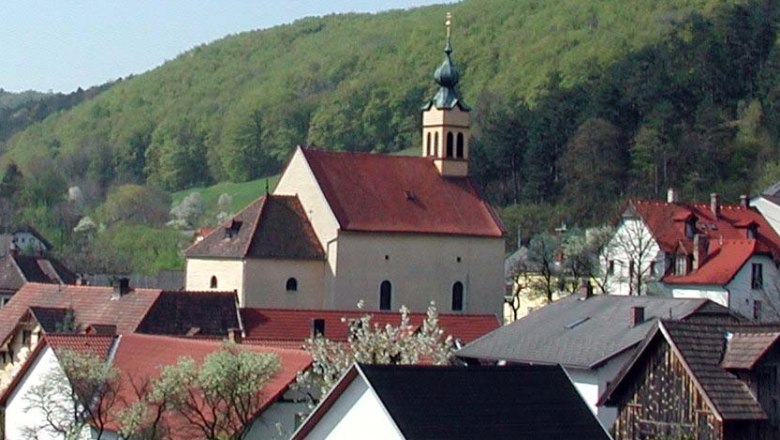 Maria Raisenmarkt pilgrimage church in a rural setting with hills in the background.