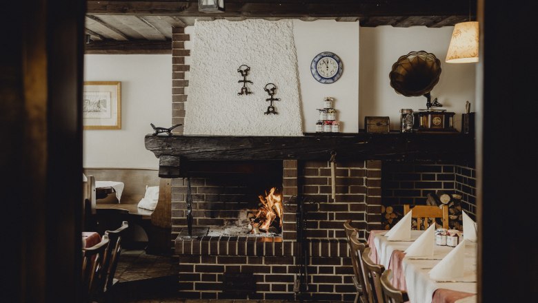 Cozy restaurant with fireplace, rustic furnishings and table setting.