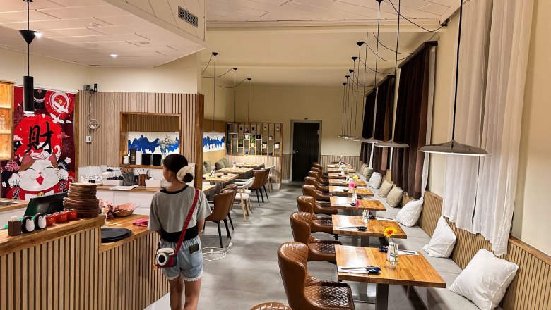 Interior view of a modern restaurant with wooden tables and leather armchairs.