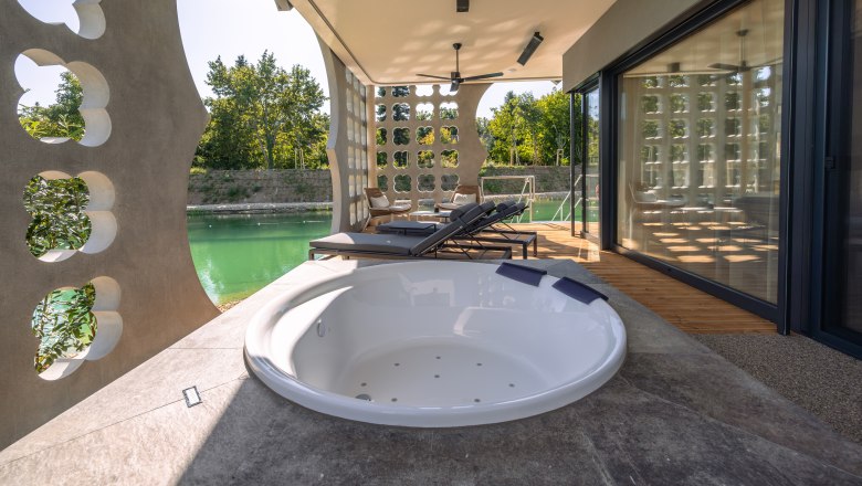 Terrace with whirlpool and sun loungers, view of a pond.