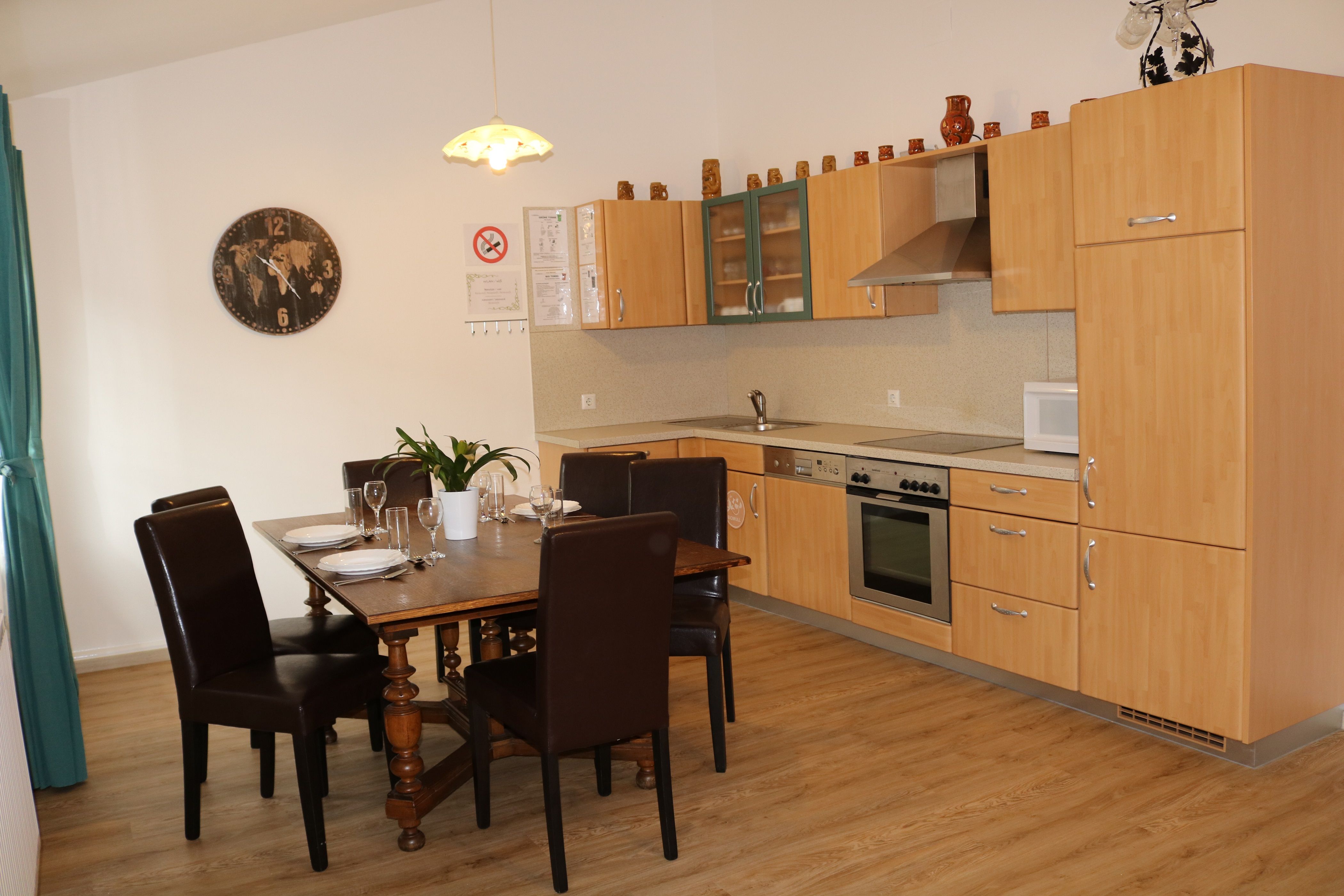 Dining area with wooden table and chairs, next to a modern kitchen with wooden cupboards.