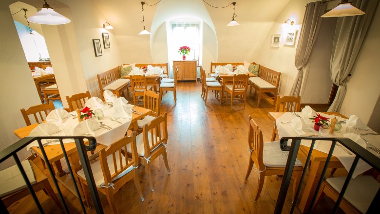 Cozy restaurant with wooden furniture and white-clothed tables.