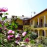 A sunny courtyard with a yellow building, white columns and blooming pink flowers in the foreground.