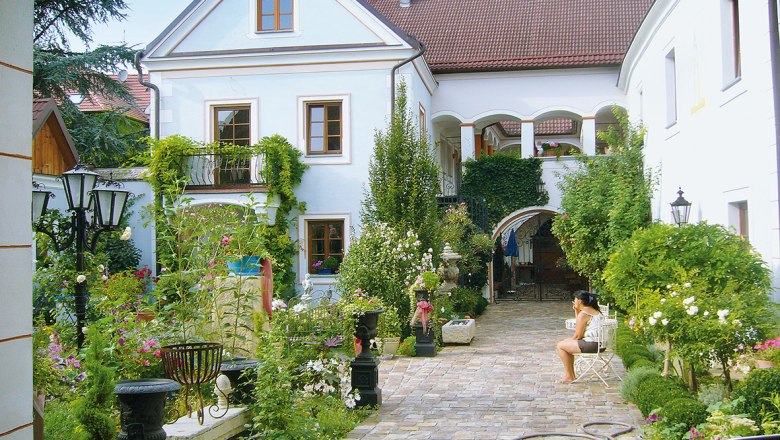 Renaissancehof Kerschner, © Renaissancehof Kerschner An idyllic courtyard with plants and a seated person.