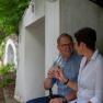 A couple sits in a wine cellar lane and toasts with glasses of wine.