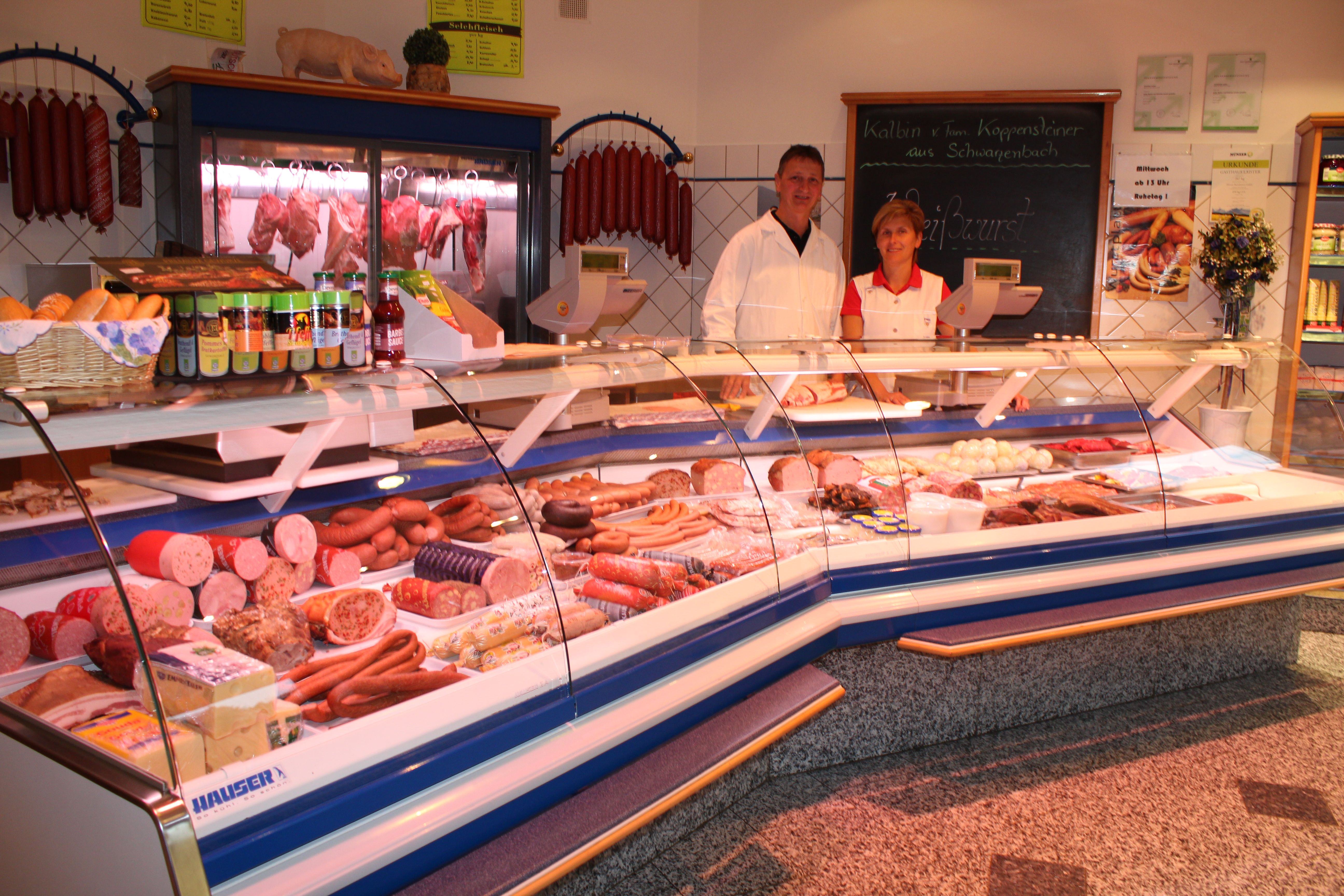 Two people behind a meat counter in a butcher's shop.