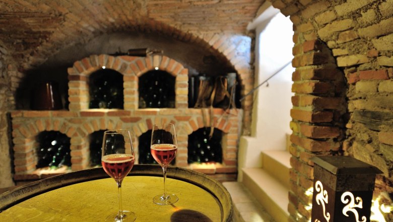 Wine cellar with two glasses of rosé wine on a barrel.