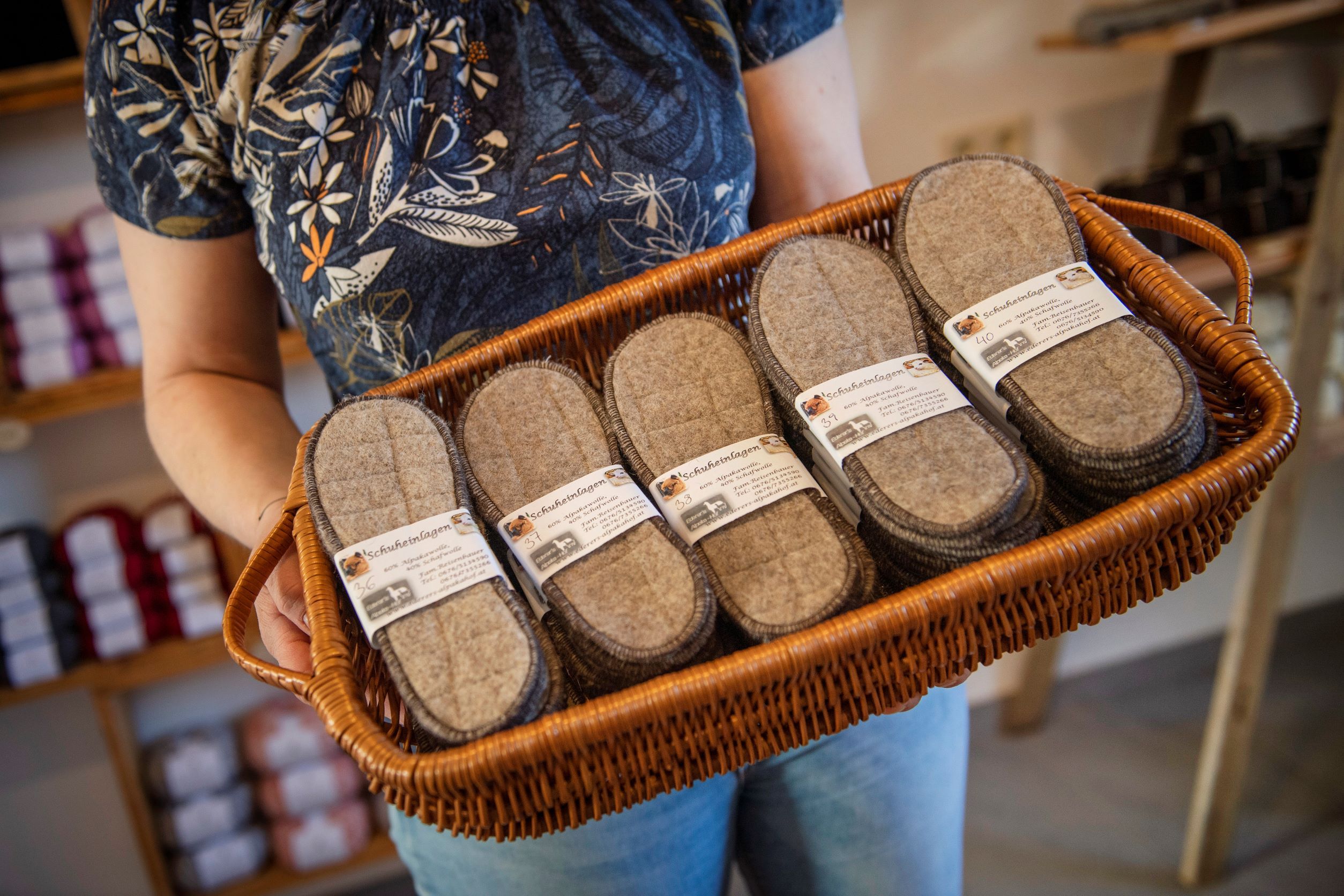 Person holding a basket of felt shoe insoles in a farm store.