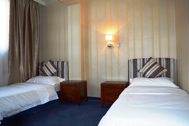 Room 8, © Hotel Austria A hotel room with two single beds, bedside tables and a wall lamp.