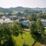 Aerial view of buildings in a green, hilly landscape.