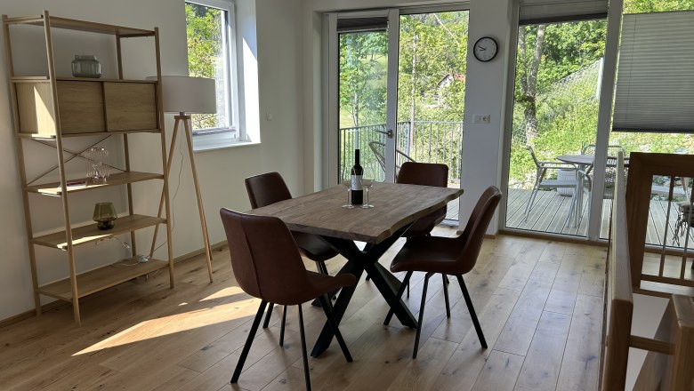 Dining room with wooden table, brown chairs and view of the terrace and garden.