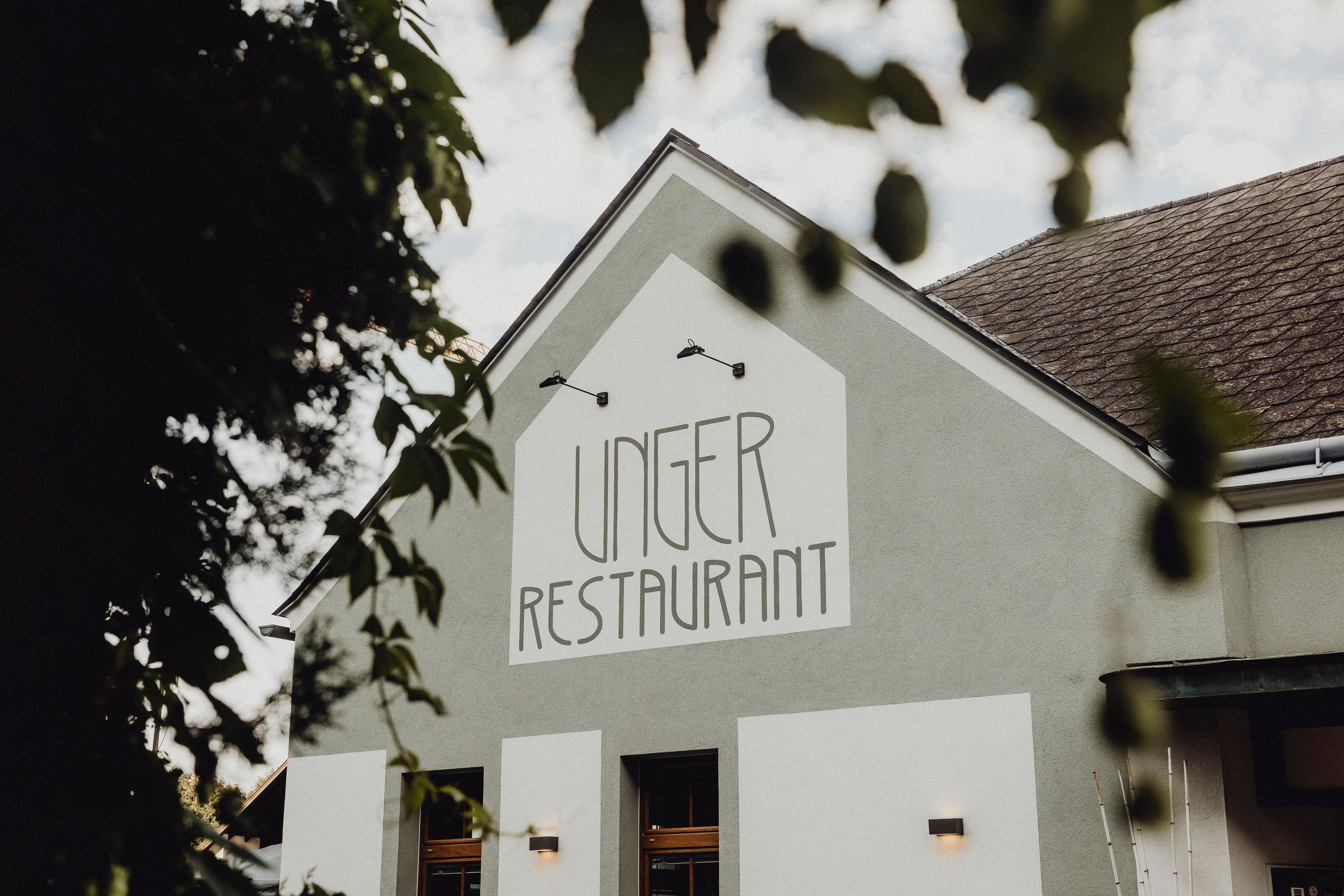 Exterior view of the Unger Restaurant with green building and lettering.