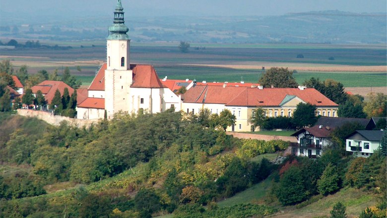 Aerial view of the parish church of St. Agatha on a hill with surrounding buildings and landscape.