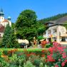 A picturesque hotel with colorful flowers in the foreground and a castle in the background.