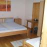 A simply furnished bedroom with a double bed, wooden furniture and a painting on the wall.