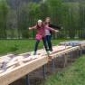 Two girls balance on a wooden course outdoors.
