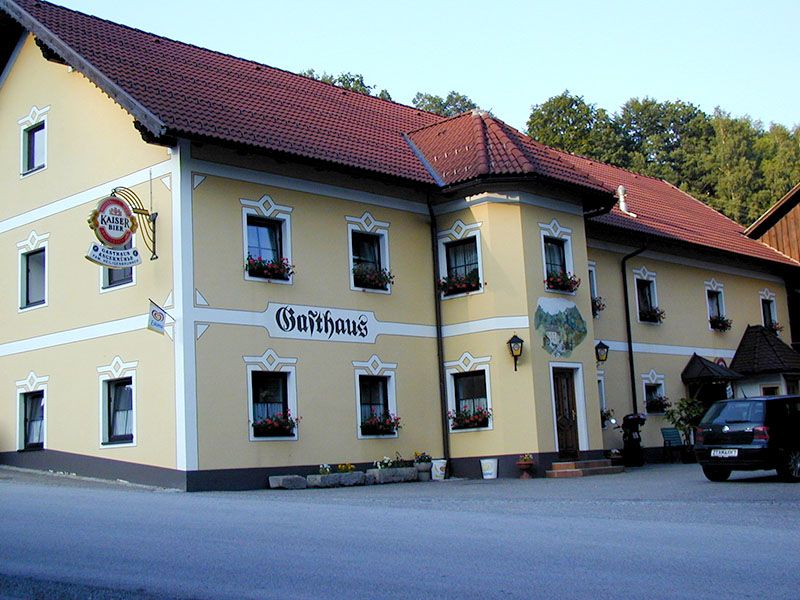 A traditional inn with a yellow façade and red roof tiles.