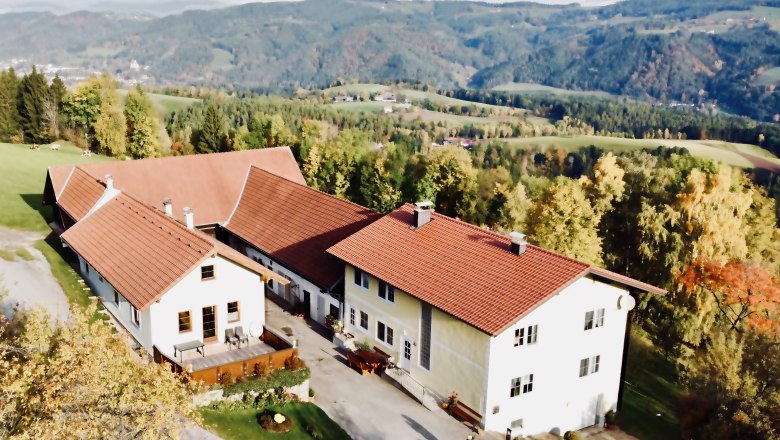 Aerial view of a farm with red roofs in a hilly landscape.