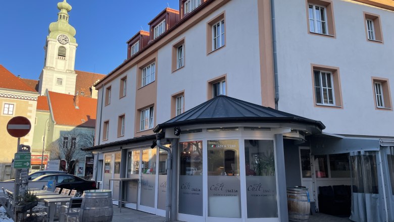 Exterior view of a restaurant with the inscription 'Cult Italia' and a church tower in the background.