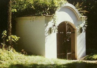 White mausoleum with metal gate in the forest.