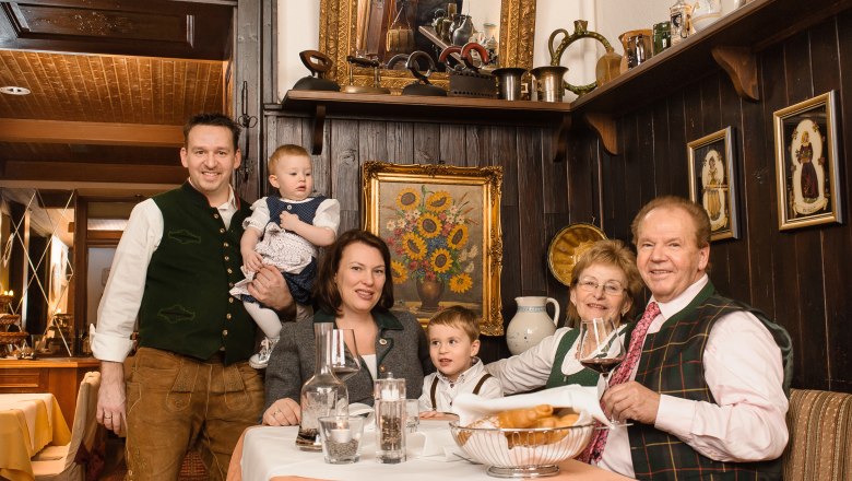 A family in traditional dress sits at a table in a rustic restaurant.