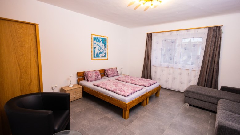 Bedroom with double bed, sofa and armchair.