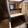 Bathroom with brown tiles, double washbasin, bathtub and mirror.