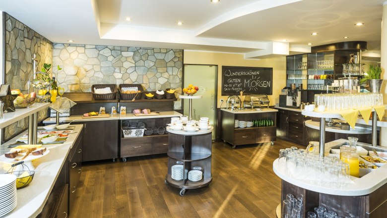 A breakfast buffet with a variety of food and drinks in a bright room.