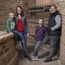 A family stands in front of a brick wall in a wine cellar.