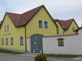 Yellow building with red roof and green gates, labeled 'Guest House'.