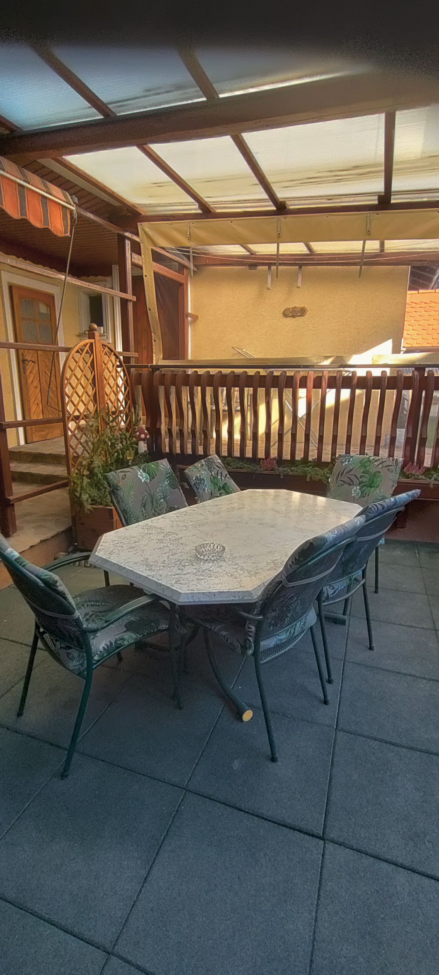 Covered terrace with table and chairs.