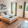 Modern guest room with double bed, green curtains and wall decoration at Hubertushof Poysdorf.
