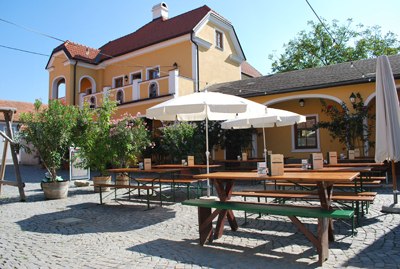 A cozy courtyard with wooden tables and benches in front of a yellow building.