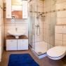 Modern bathroom with shower, washbasin, WC and blue bath mat.
