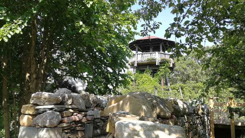 Observation tower of the Langenlois garden school surrounded by trees and a stone wall.