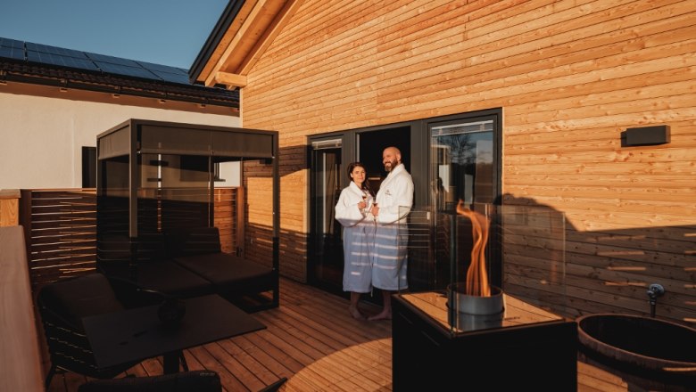 Terrace with four-poster bed, fireplace and two people in bathrobes.