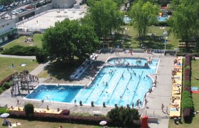 Luftaufnahme eines Freibads mit Schwimmbecken und Liegewiese.