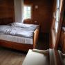 A cozy room with wooden walls and a double bed in the Vorderötscher shelter.