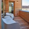 Modern balcony with wooden walls and white chairs.