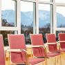 Seminar room with red chairs and mountain views through large windows.
