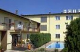 Exterior view of a yellow hotel with pool and garden.