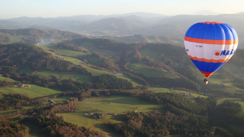 Hot air balloon over the green hilly landscape of the Traisental.