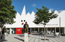 Exterior view of the Caricature Museum Krems with statues and trees.