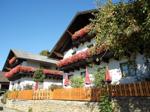 Traditional farmhouse with flowers on the balconies and a wooden fence in the foreground.
