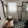 Modern bathroom with white tiled walls, black and white checkerboard floor, washbasin, mirror and shower.
